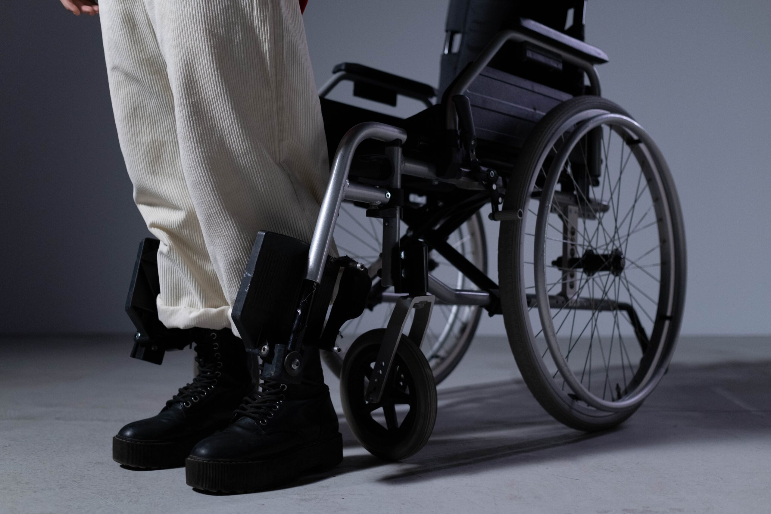 Person Wearing Black Boots Standing in front of a Wheelchair